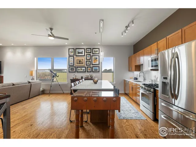 a kitchen with stainless steel appliances granite countertop a refrigerator a sink dishwasher a dining table and chairs with wooden floor