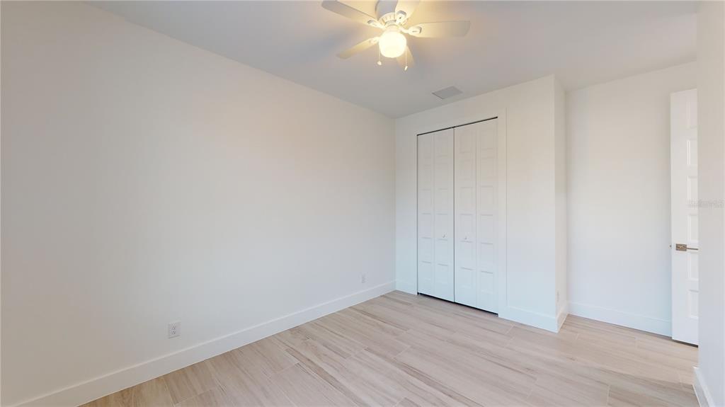 10510 Rainsville Street Port Charlotte, FL 33981 - Photo 22 of 37 an empty room with wooden floor and fan