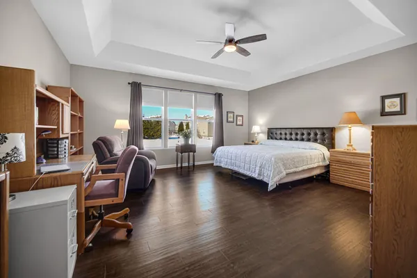 a bedroom with a bed chairs and wooden floor