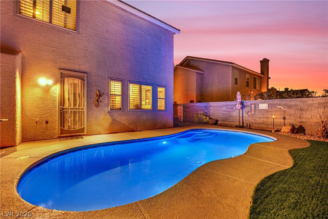 1724 Millstream Way Henderson, NV 89074 - Photo 56 of 60 An inviting backyard oasis features a freeform pool, perfect for twilight relaxation under painted skies.