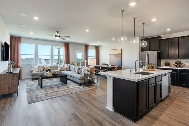 a large kitchen with stainless steel appliances kitchen island granite countertop a sink dishwasher a refrigerator and a dining table with wooden floor