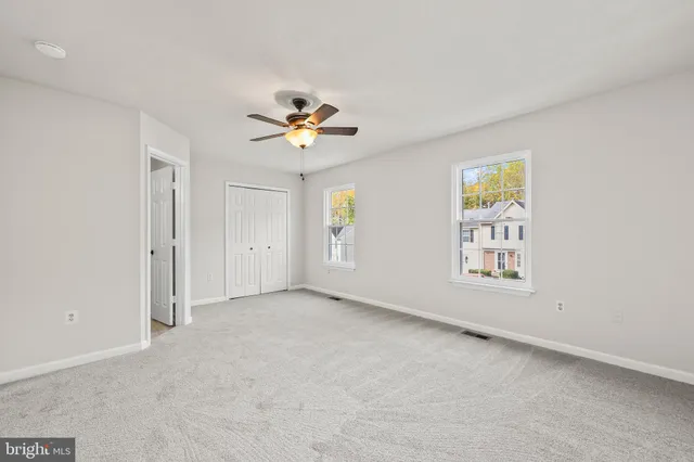 a view of an empty room with chandelier fan and fire place