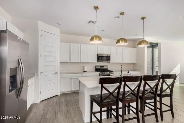a kitchen with stainless steel appliances kitchen island granite countertop a table chairs and a sink