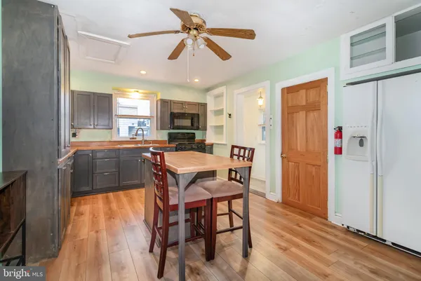 a kitchen with stainless steel appliances a dining table chairs refrigerator sink and cabinets