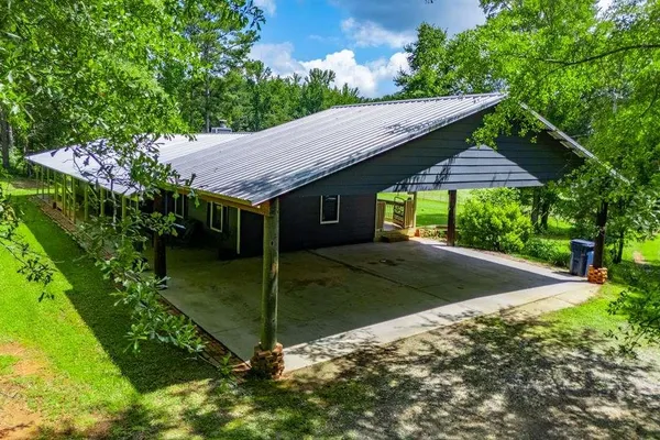 a view of a house with a yard plants and large tree