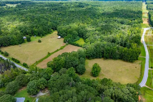 an aerial view of residential house with outdoor space and trees all around