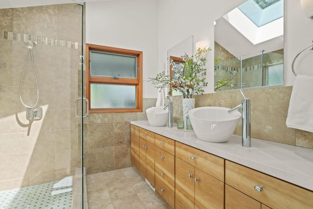 a spacious bathroom with a granite countertop sink a mirror and shower