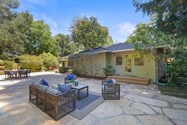 a view of a patio with couches and table and chairs with wooden fence and plants