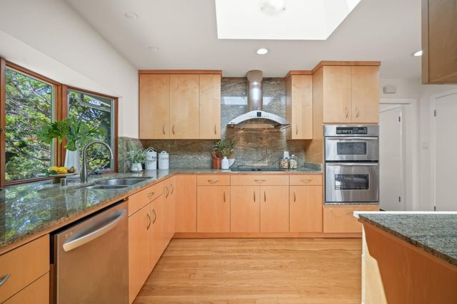 a kitchen with stainless steel appliances granite countertop a refrigerator a stove and a sink