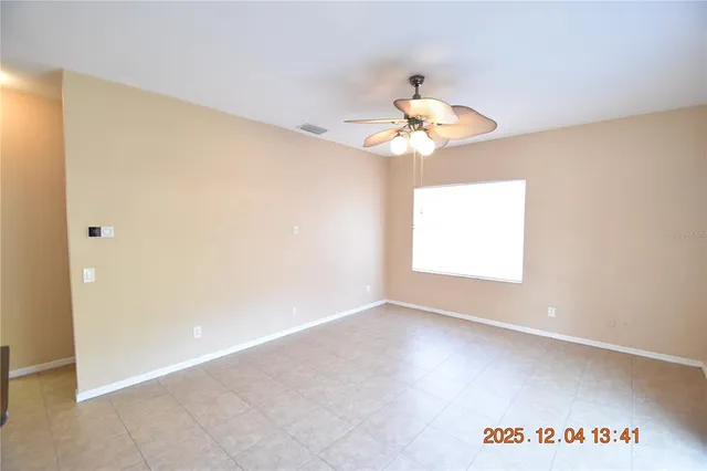an empty room with windows and chandelier fan