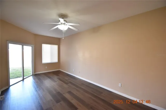 an empty room with wooden floor fan and windows