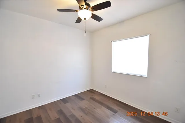 an empty room with a window and a ceiling fan