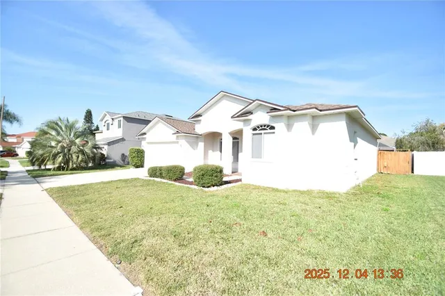 a view of a white house next to a yard with potted plants