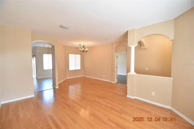 a view of an empty room with wooden floor and a bathroom