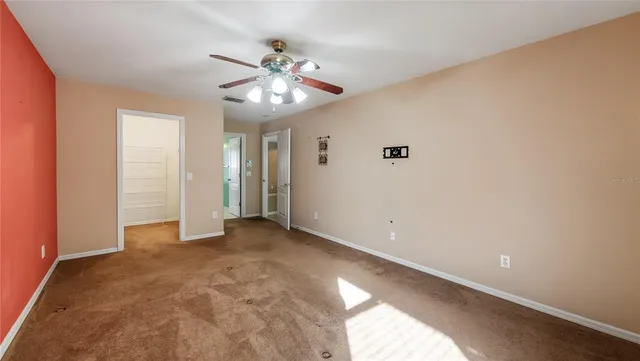 a view of an empty room with a chandelier fan
