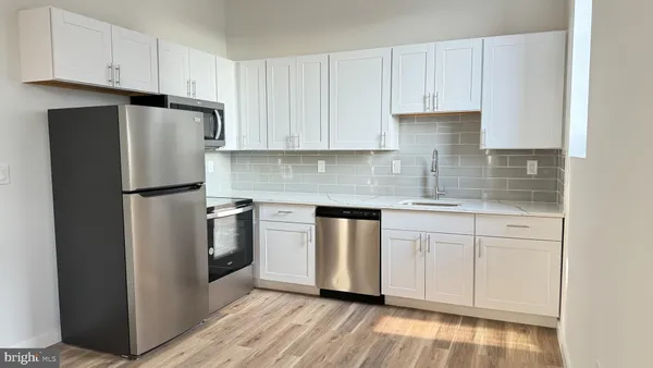 a kitchen with stainless steel appliances granite countertop a refrigerator sink and white cabinets