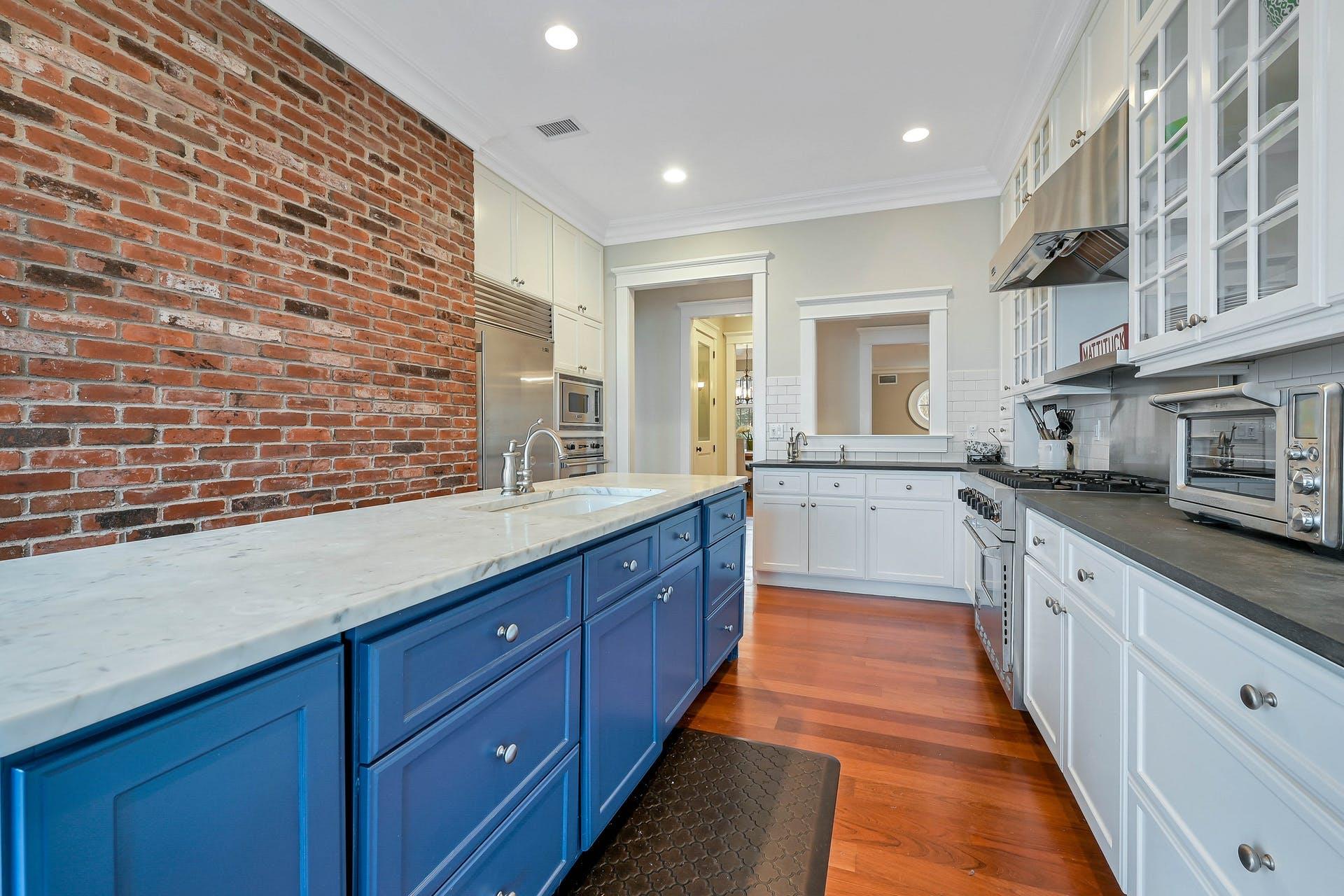 580 Lloyds Lane Mattituck, NY 11952 - Photo 13 of 30 Kitchen with dark hardwood / wood-style flooring, backsplash, brick wall, blue cabinets, and built in appliances