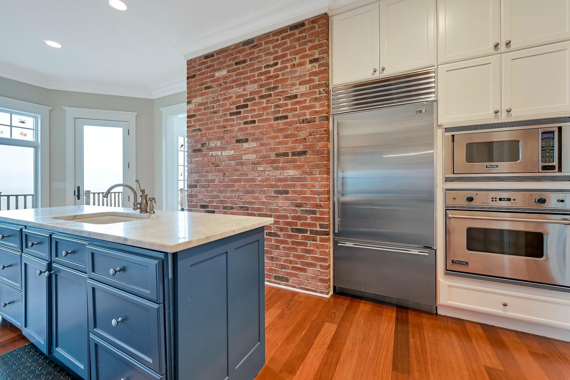 580 Lloyds Lane Mattituck, NY 11952 - Photo 14 of 30 Kitchen featuring ornamental molding, brick wall, blue cabinets, sink, and built in appliances