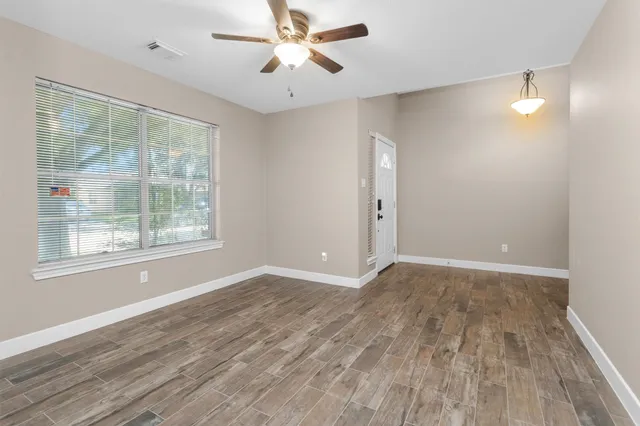 a view of an empty room with wooden floor and a window