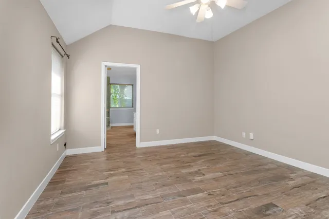 a view of an empty room and window and chandelier fan