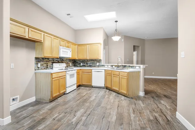 a kitchen with a sink cabinets wooden floor and stainless steel appliances