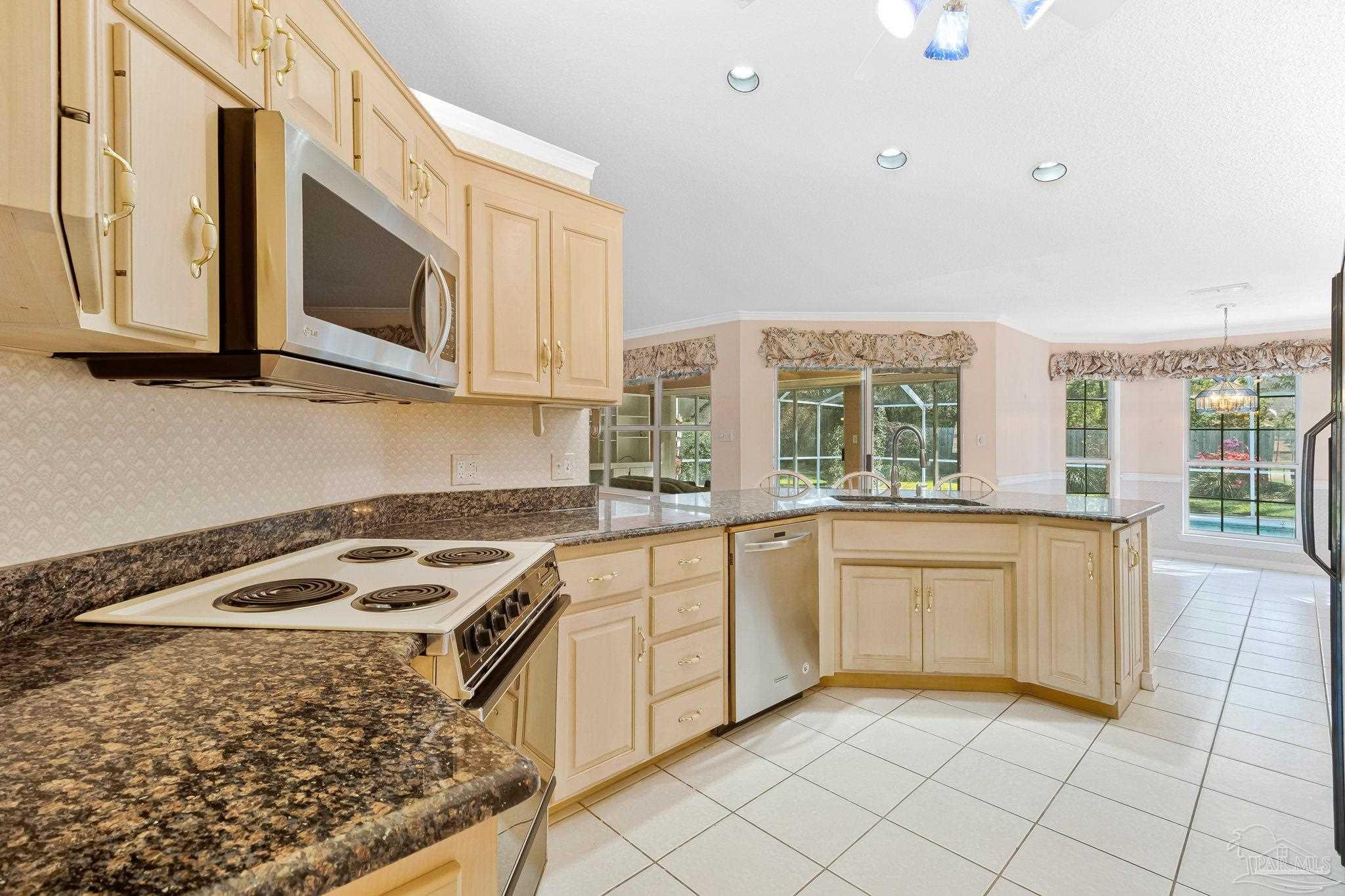 9320 Bell Ridge Drive Pensacola, FL 32526 - Photo 31 of 55 a kitchen with stainless steel appliances granite countertop a stove a sink and a microwave