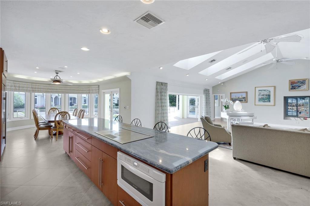 2147 Snook Drive Naples, FL 34102 - Photo 48 of 50 Kitchen featuring ceiling fan, open floor plan, a center island, wood finish cabinets, and a skylight