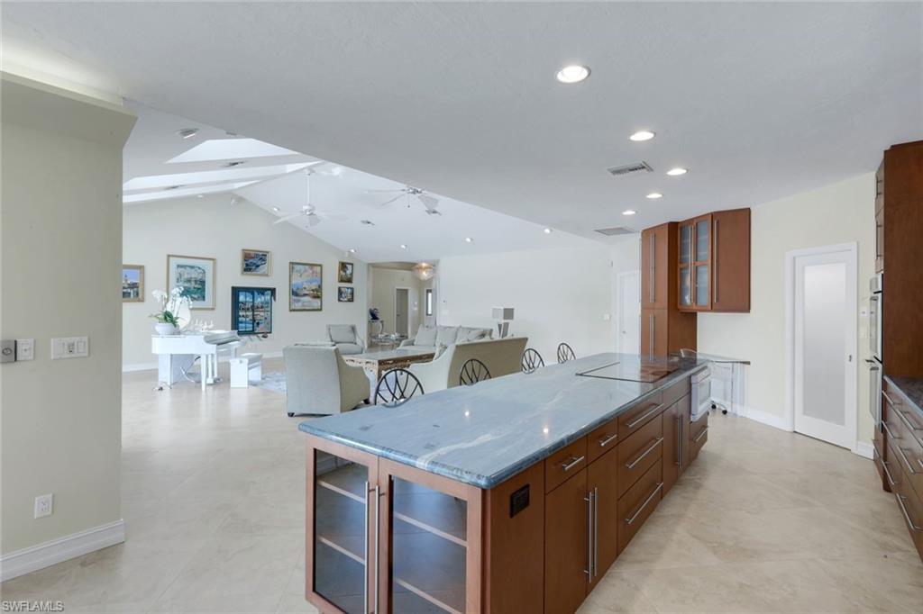 2147 Snook Drive Naples, FL 34102 - Photo 49 of 50 Kitchen with glass fronted cabinets, open floor plan, dark stone counters, wood finish cabinets, and vaulted ceiling