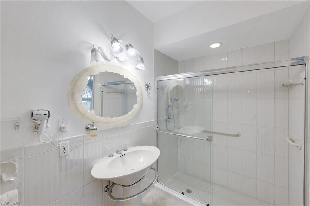 2147 Snook Drive Naples, FL 34102 - Photo 23 of 50 Full bath featuring a wainscoted wall, a shower stall, and tile walls