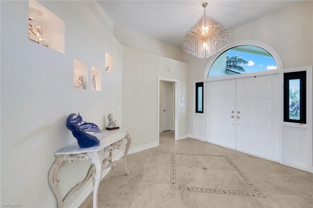 2147 Snook Drive Naples, FL 34102 - Photo 3 of 50 Entryway featuring hanging lights, a high ceiling, and inlaid floor details