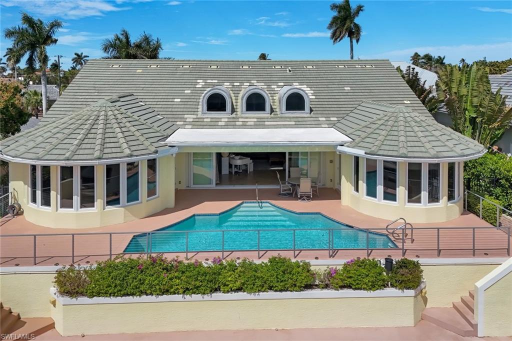 2147 Snook Drive Naples, FL 34102 - Photo 38 of 50 Back of house featuring a sunroom, a tiled roof, stucco siding, a patio, and an outdoor pool