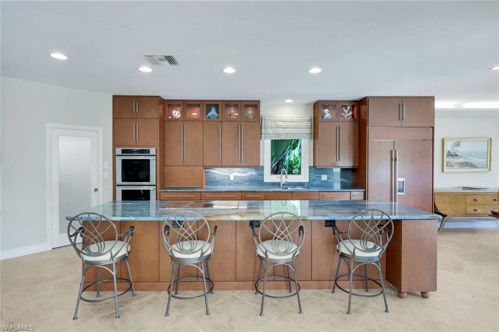 2147 Snook Drive Naples, FL 34102 - Photo 9 of 50 Kitchen featuring a kitchen breakfast bar, tasteful backsplash, built in refrigerator, dark stone countertops, and recessed lighting