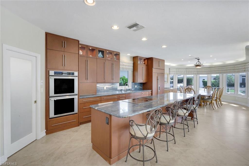 2147 Snook Drive Naples, FL 34102 - Photo 10 of 50 Kitchen with a breakfast bar area, dark stone countertops, double oven, a spacious island, and wood finish cabinetry