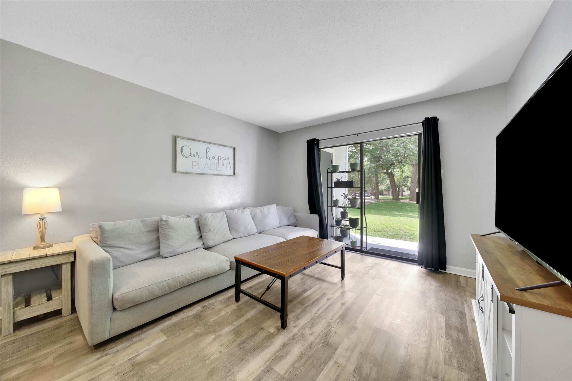 13151 Walden Road, Unit 119 Montgomery, TX 77356 - Photo 13 of 28 This cozy living room features a neutral color palette, sliding glass doors open to a lush outdoor view, enhancing the space with natural light.