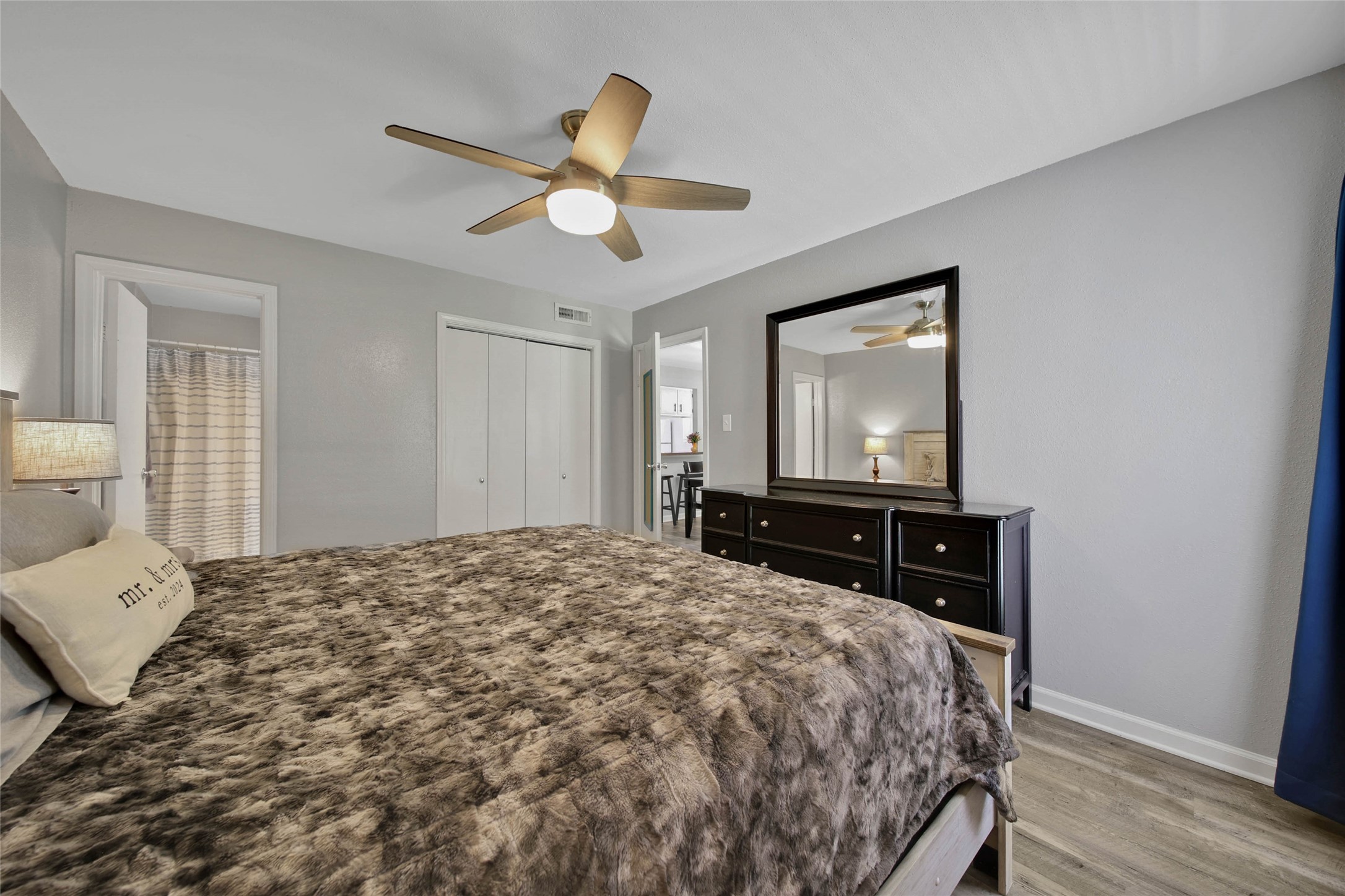 13151 Walden Road, Unit 119 Montgomery, TX 77356 - Photo 16 of 28 This cozy bedroom features a modern ceiling fan, ample natural light, neutral color palette and neutral flooring create a warm and inviting atmosphere. A doorway leads to a bathroom, enhancing convenience.
