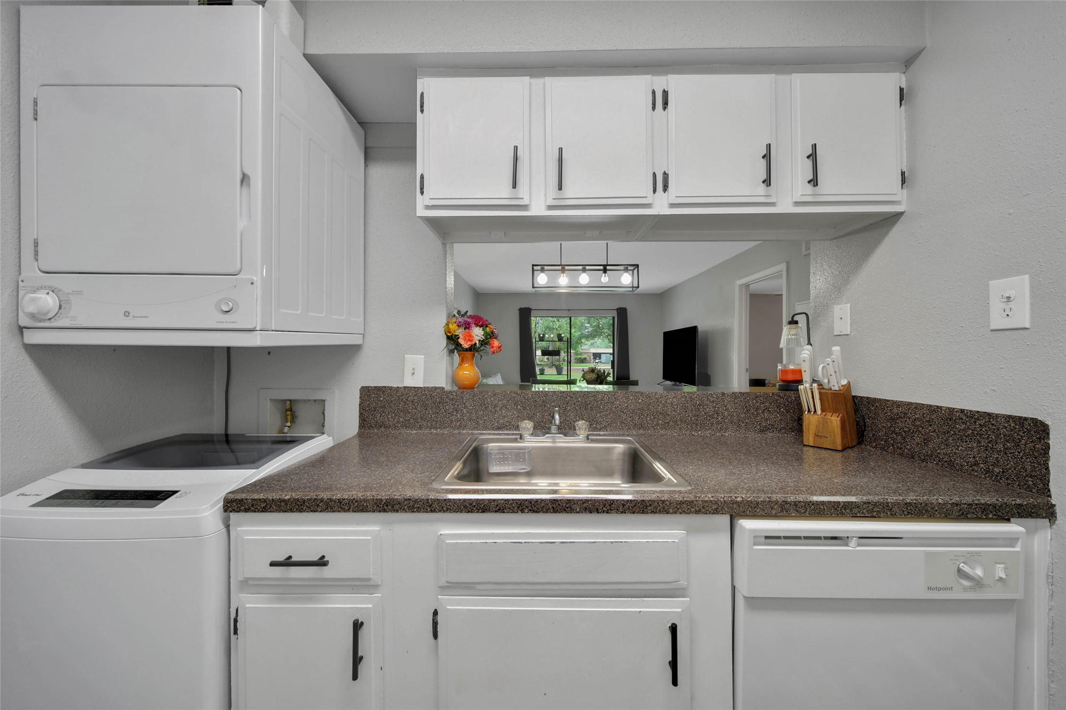 13151 Walden Road, Unit 119 Montgomery, TX 77356 - Photo 9 of 28 This kitchen features a compact and efficient layout with white cabinetry boasting updated hardware. Open bar top with seating provides a view into the living area, adding a sense of openness and continuity in the common space!