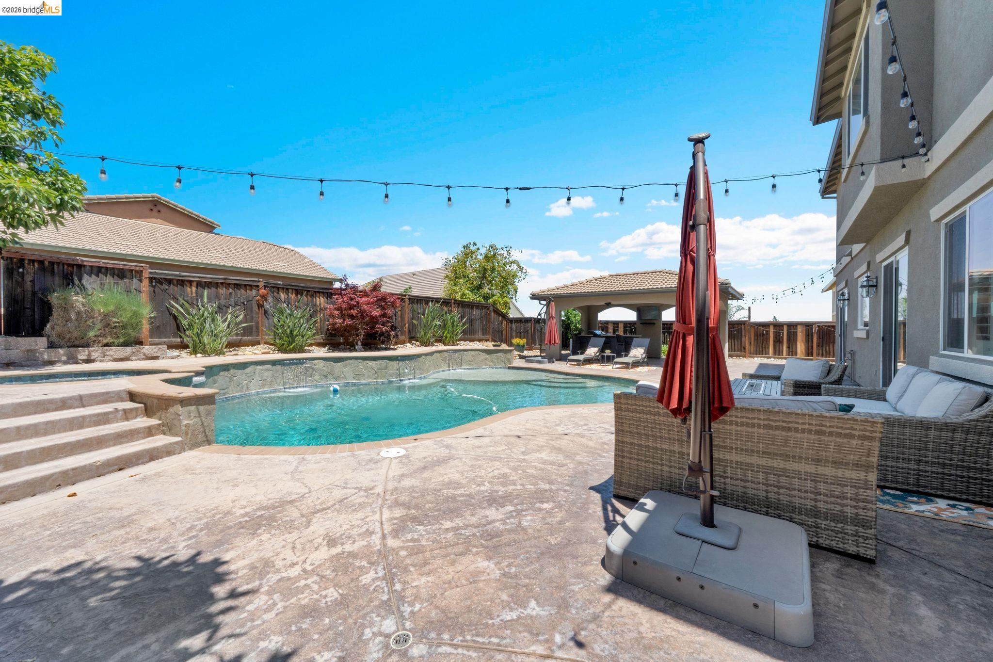 2513 Winged Foot Road Brentwood, CA 94513 - Photo 30 of 45 Spacious backyard featuring a curvilinear swimming pool, concrete patio, and pergola-covered outdoor lounge area