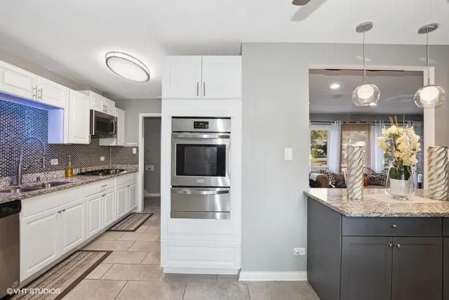 a kitchen with kitchen island granite countertop a sink and stainless steel appliances
