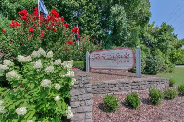a view of a stone house with a small yard and large trees
