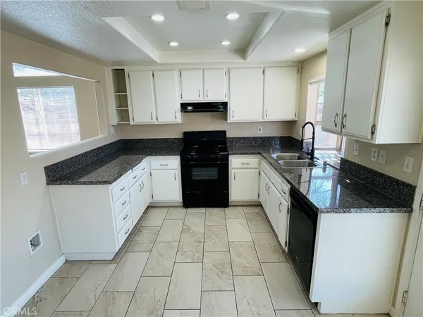 a large kitchen with a stove top oven a sink a counter space and cabinets