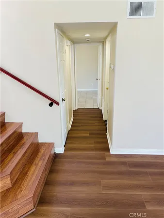 a view of a hallway with wooden floor and staircase