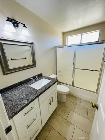 a bathroom with a granite countertop sink a toilet and mirror