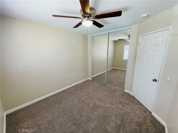 an empty room with a ceiling fan and window