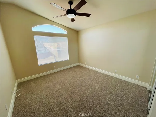 an empty room with closet and a ceiling fan