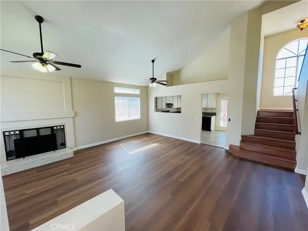 a view of an empty room with wooden floor fireplace and a window