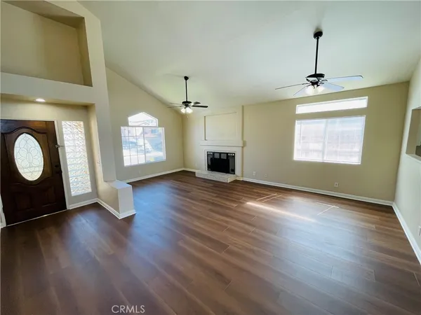 an empty room with wooden floor windows and fireplace