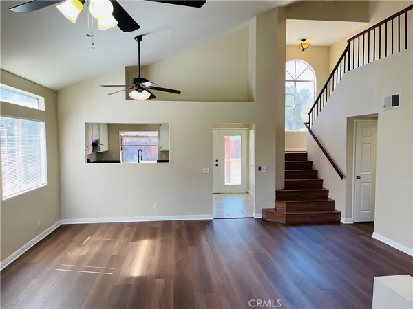 a view of a livingroom with wooden floor staircase and a ceiling fan