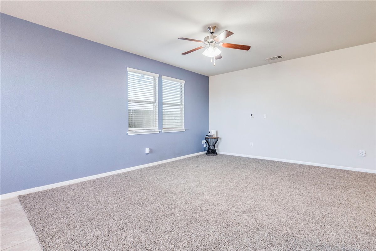312 Triumph Road Buda, TX 78610 - Photo 12 of 36 an empty room with windows and chandelier fan
