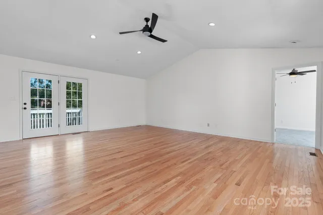 a view of empty room with wooden floor and windows