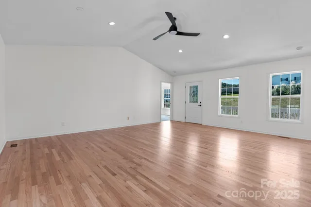 a view of empty room with wooden floor and windows